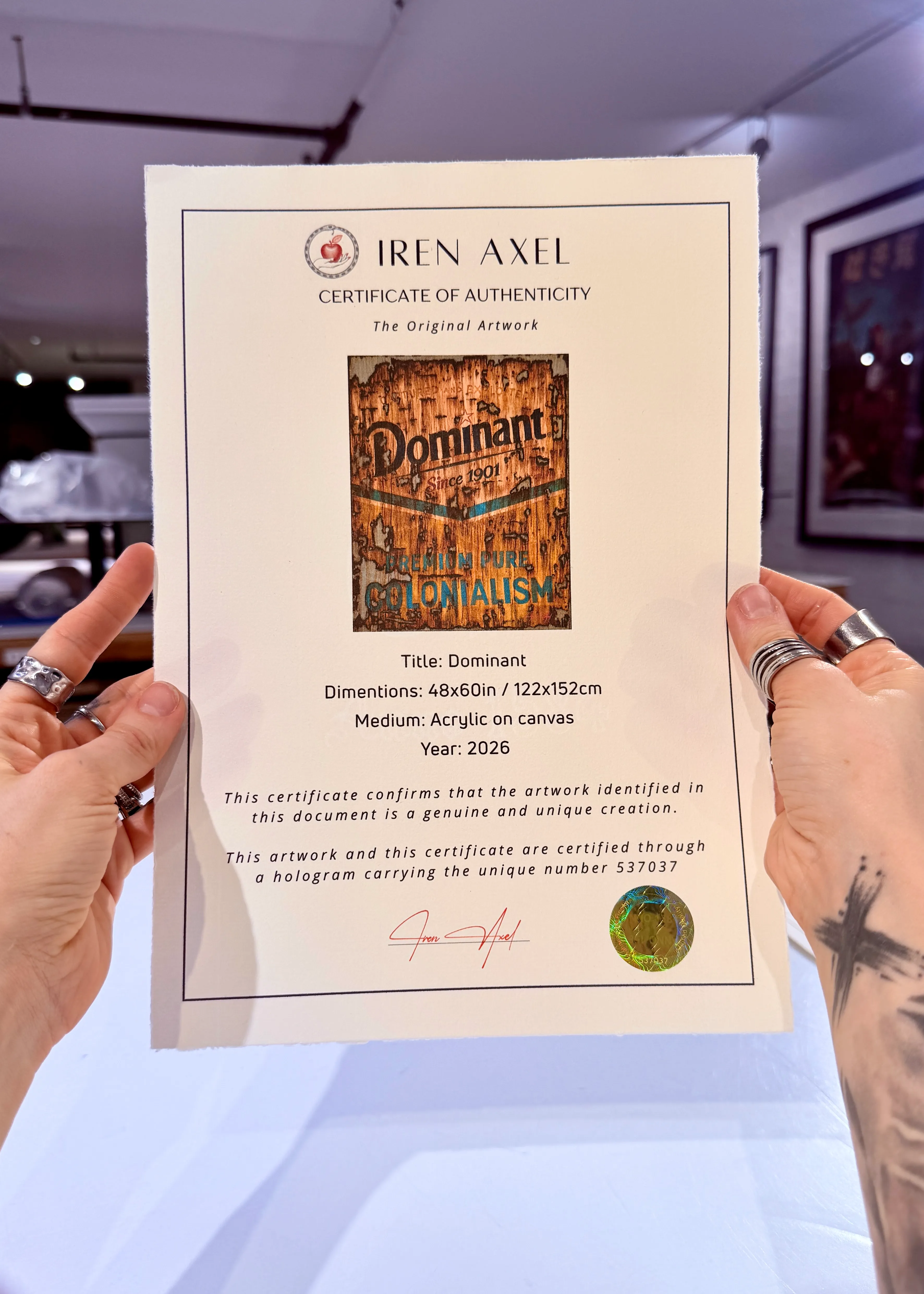 The signed certificate of authenticity for Dominant, hologram number 537037, held up in the gallery