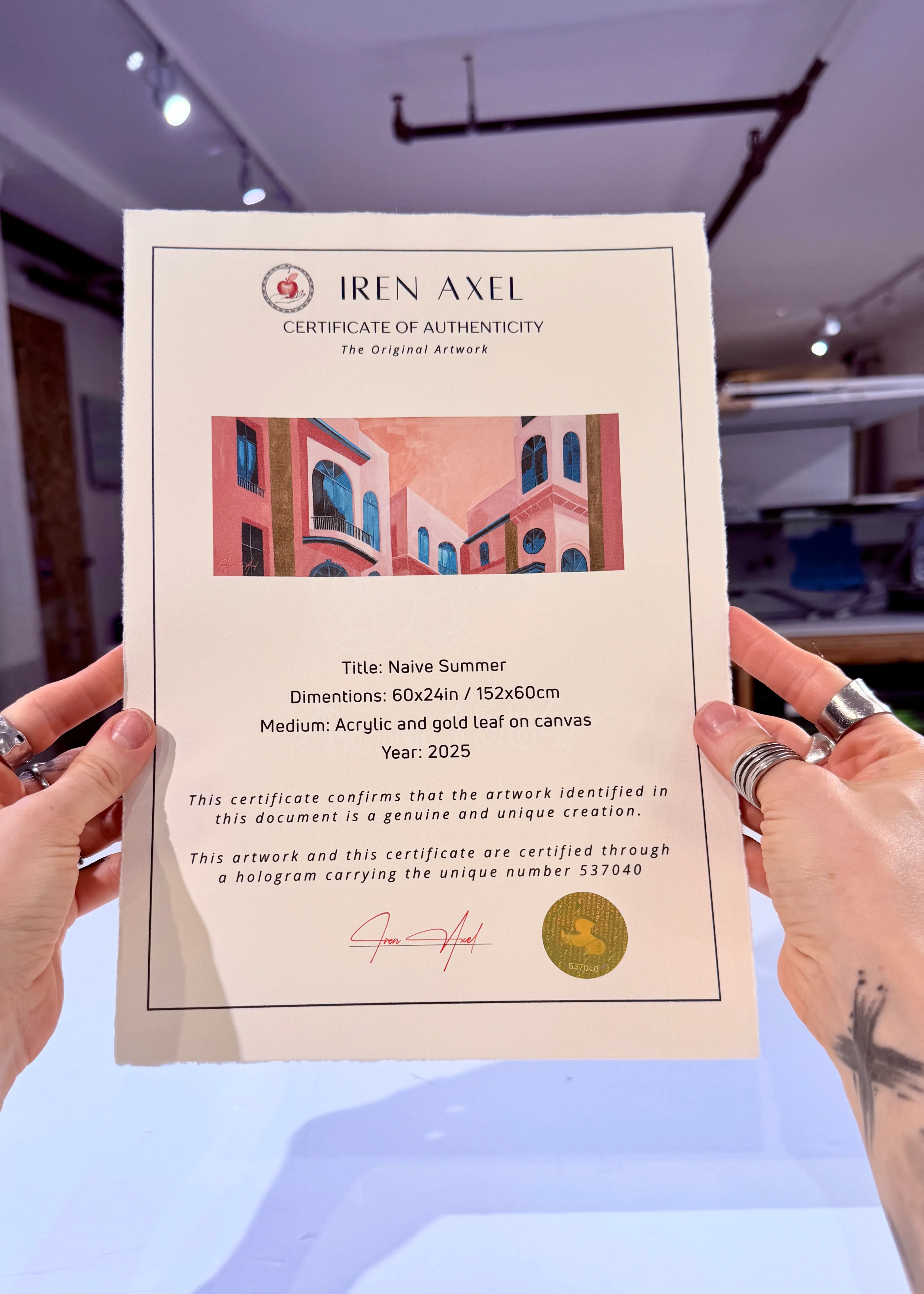 The signed certificate of authenticity for Naive Summer, hologram number 537040, held up in the gallery