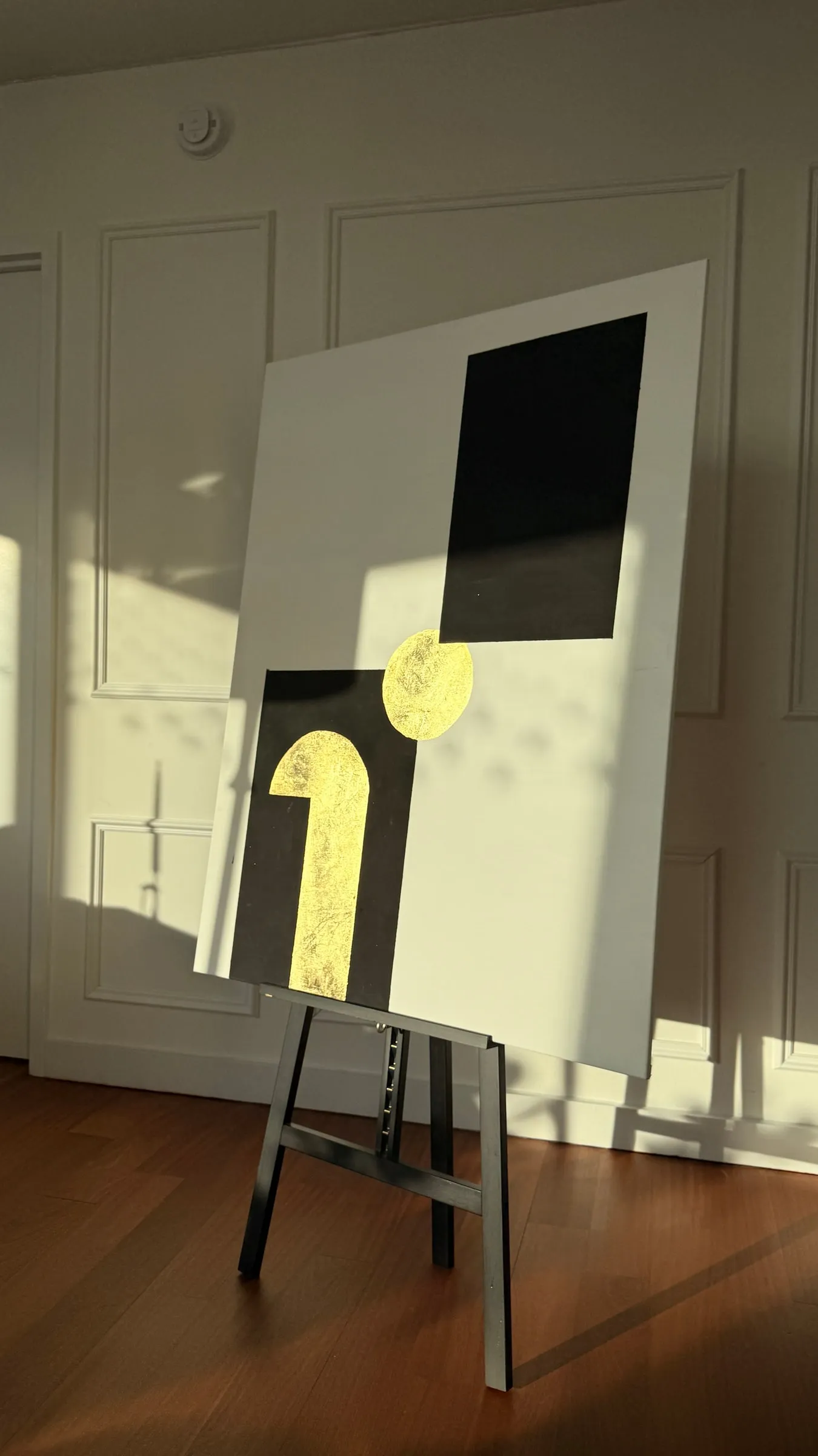 IAMART on a black easel in evening sunlight, against a white panelled wall